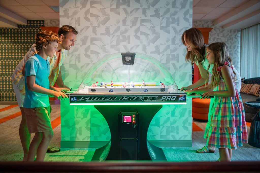 Family of four playing bubble hockey in game room at Hotel Landy in Orlando, Florida