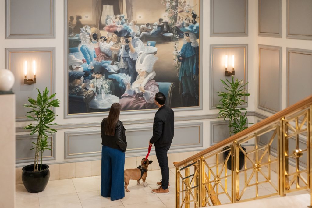 Couple with dog on a leash looking at painting on stairwell landing at The Rittenhouse Hotel in Philadelphia