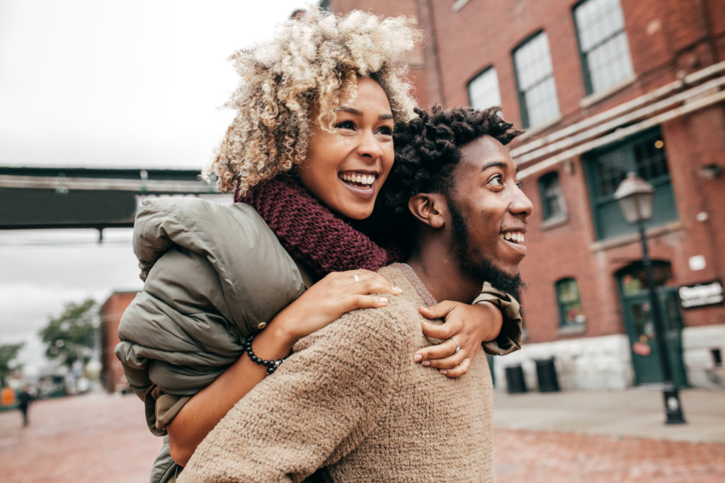 Woman piggbacking on her significant other as they explore a city