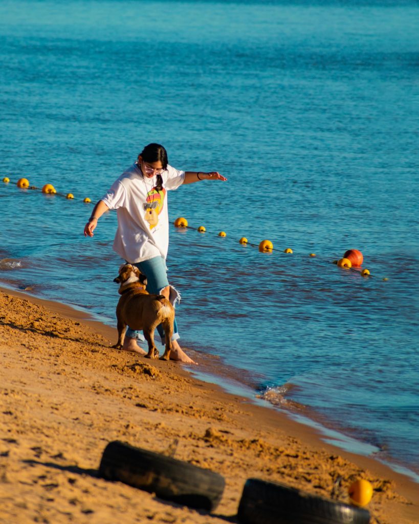 Woman walking along a coastline with her dog